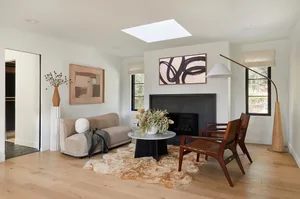 Minimalist living room with hardwood flooring, geometric art, and a fireplace.