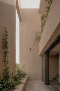 A concrete exterior wall with lush greenery and large sliding glass doors.