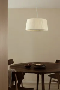 Modern dining room with wooden table and chairs under a pleated light fixture.