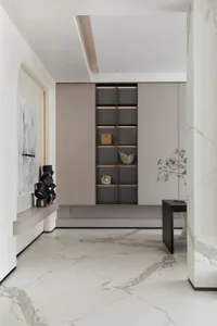 Modern entrance hall designed with marble flooring and walls, featuring a minimalist bookshelf and a contemporary table.