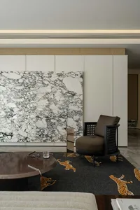 A modern living room with marble accent wall, round wooden coffee table, and leopard-patterned rug.