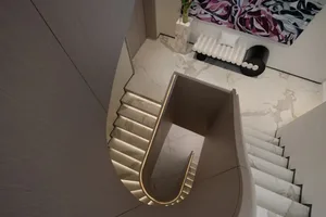 A modern interior staircase with marble steps and a light-colored wall