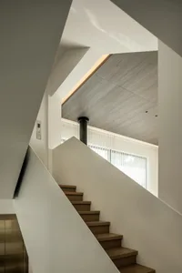 Modern, minimalist stairway with wooden steps and white walls.