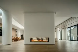 A modern living room featuring concrete and glass materials with a cozy fireplace.