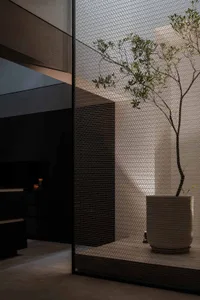 A modern living room featuring a metal net partitioning a space with a potted tree.