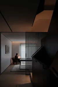 Person sitting on wooden lounge chair in modern living room with minimalist decor.