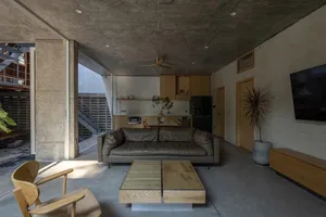 A minimalist living room with concrete walls and a grey sofa.