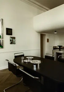 A modern minimalist dining room featuring metallic tableware and sleek, black dining table and chairs with chrome accents.