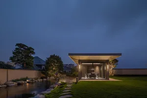Modern outdoor living space featuring concrete and glass during dusk.