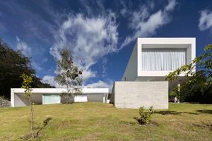 A modern residential exterior with concrete walls and glass windows.