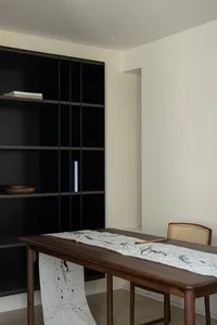 A modern workspace featuring a wooden table with lacquer details and a minimalist chair.
