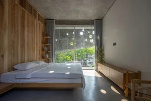 Minimalist bedroom with wood and concrete design elements and a blurred tree view through the window.