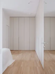 Minimalist bedroom with light-colored wooden flooring and simple, clean lines.