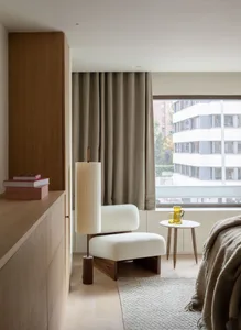 Modern minimalist bedroom featuring sleek white furniture, wooden accents, and floor-to-ceiling windows draped with sheer fab