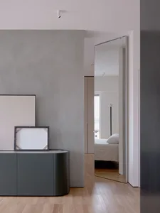A modern minimalist bedroom with concrete walls, a wood floor, and a white bed