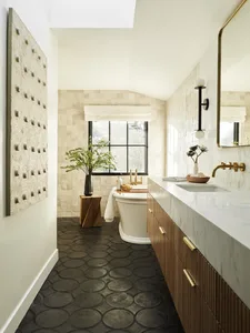A modern bathroom featuring a tile floor, freestanding bathtub, and marble countertop.