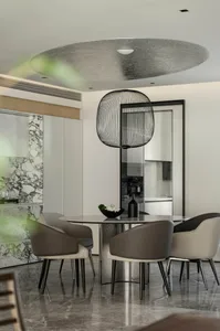 Modern dining room with marble table, gray and beige leather chairs, and a round wire pendant light hanging from the ceiling.