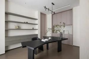 Modern home office with black wood table, minimalist design, and white shelves.