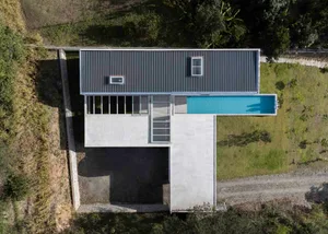 A modern house with a concrete floor plan, featuring a rooftop deck, large windows, and a swimming pool.