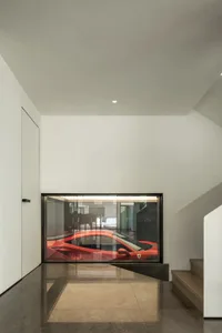 Modern interior design featuring a glass garage door with a sleek, red sports car visible through it.