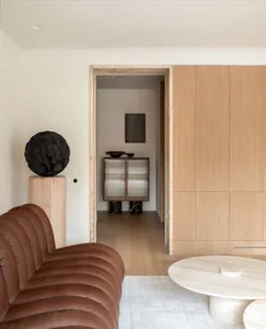 A modern living room featuring wooden cabinets, a brown leather couch, and a stone coffee table.