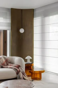 Modern living room with a sleek, glass partition and metallic accents.