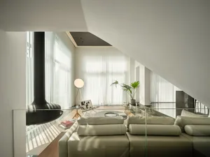 A modern living room featuring glass windows adorned with sheer white shades, a stylish leather couch, and a warm wooden floo