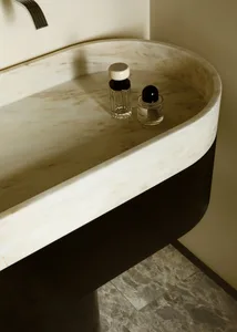 A modern bathroom counter made of marble with two small bottles on top.