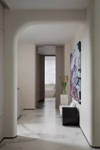 Modern interior corridor with marble flooring leading to a bathroom with a bathtub.