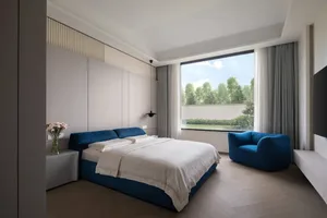 A minimalist bedroom with a blue accent chair and bed.