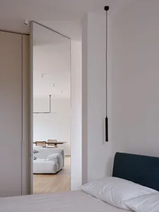 現代簡約臥室，展示一張鋪有白色床單和枕頭的床，深色床頭板，以及背景中乾淨的景色