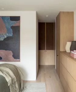 A modern minimalist bedroom featuring a wooden accent wall and built-in storage