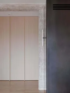 現代簡約室內空間，搭配木質衣櫃門與混凝土邊緣，呈現俐落極簡的設計風格。
