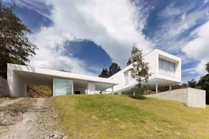 A modern white concrete home with large glass windows and a minimalist design.