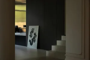 A modern living room with a metallic clad wall and abstract artwork in a minimalist style.
