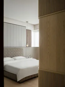 Bedroom with minimalist design, woven fabric headboard, and wooden accents.
