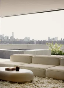 Modern, minimalist living room with beige upholstered furniture and a circular coffee table on a white rug.