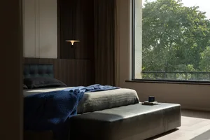Modern bedroom with fabric bedding, wooden headboard, and metallic floor lamp.