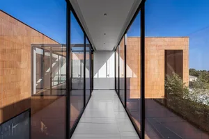 A modern glass corridor with a white floor and wooden walls.
