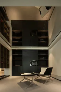 A modern office space featuring minimalist design and industrial aesthetics, with a focus on open shelving, black and grey ma