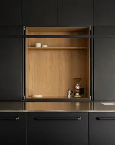 Black kitchen cabinets with a wooden storage unit containing a coffee grinder and a coffee maker.