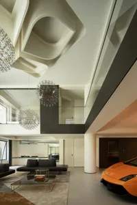 A modern living room featuring a sleek, orange sports car parked indoors, with geometric lighting fixtures and smooth, minima