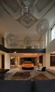 A sleek, modern interior space featuring metallic decor, high ceilings, and a luxurious car display.
