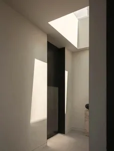 A minimalist interior design featuring a concrete wall and skylight