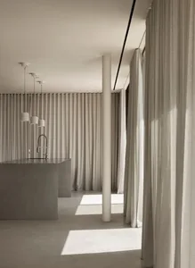 Modern minimalist kitchen with concrete elements and white curtains.