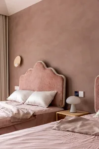 A minimalist bedroom with pink upholstered headboards and pink bedding on a bed with white pillows.