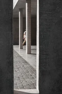 A minimalist concrete pathway with tall white columns on a grey concrete background.
