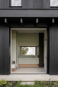A modern, minimalist bathroom with concrete walls and floor, glass partition, and a sink with a large mirror.