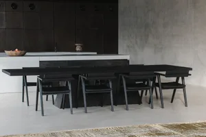 Minimalist kitchen with black furniture, concrete walls, and wood accents. Includes a dining table and chairs.