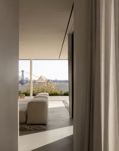 A modern, minimalist living space with concrete walls and floor, a white sectional sofa, and a floor lamp.
